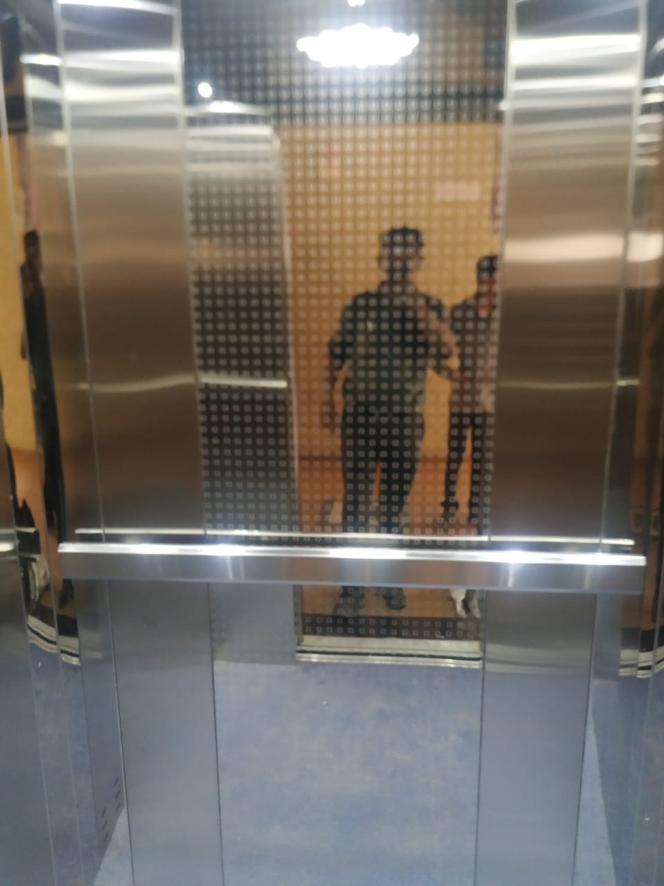 Stainless steel elevator with patterned glass and handrail